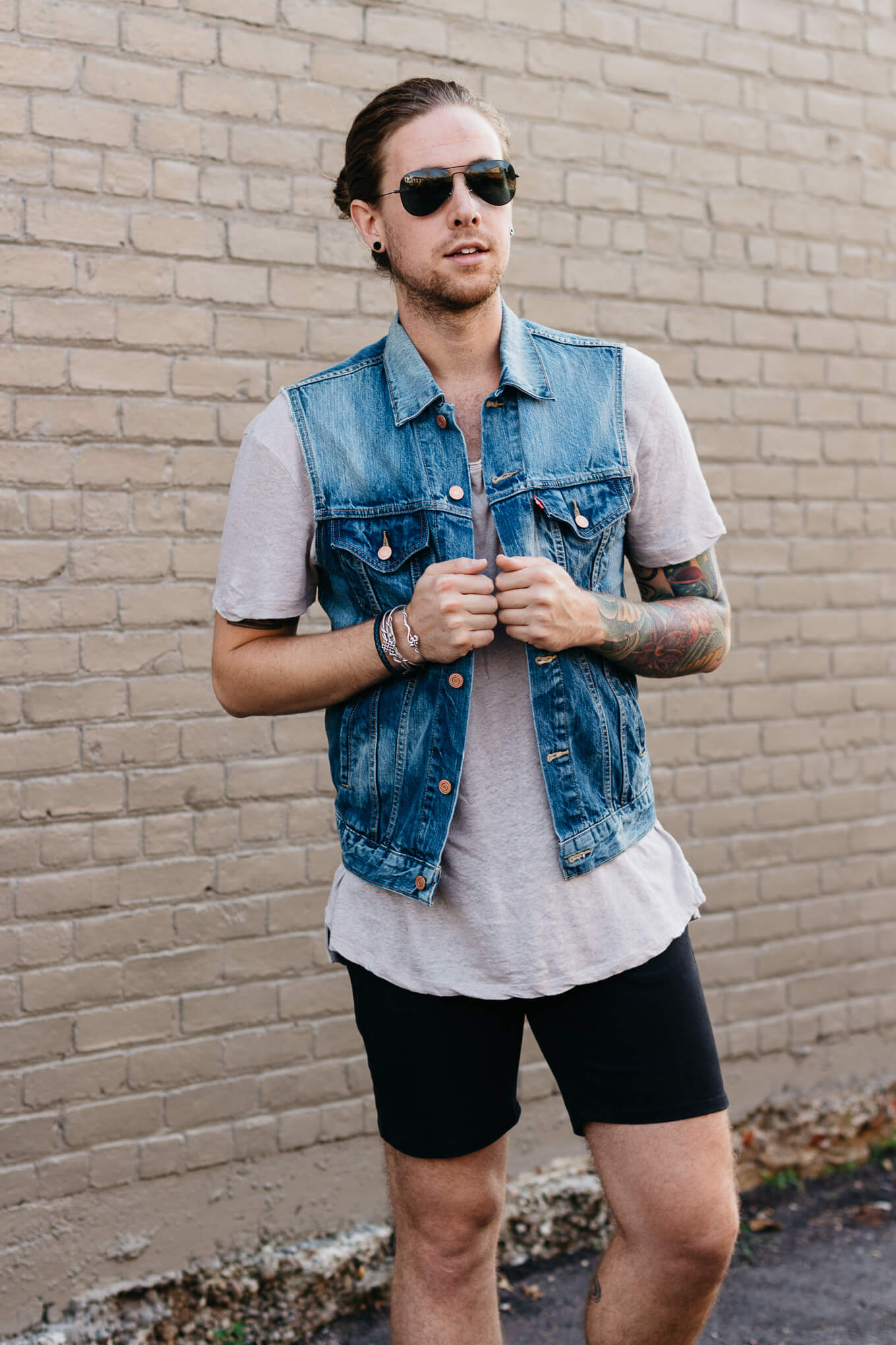 A man with a tattooed arm wearing a denim vest
