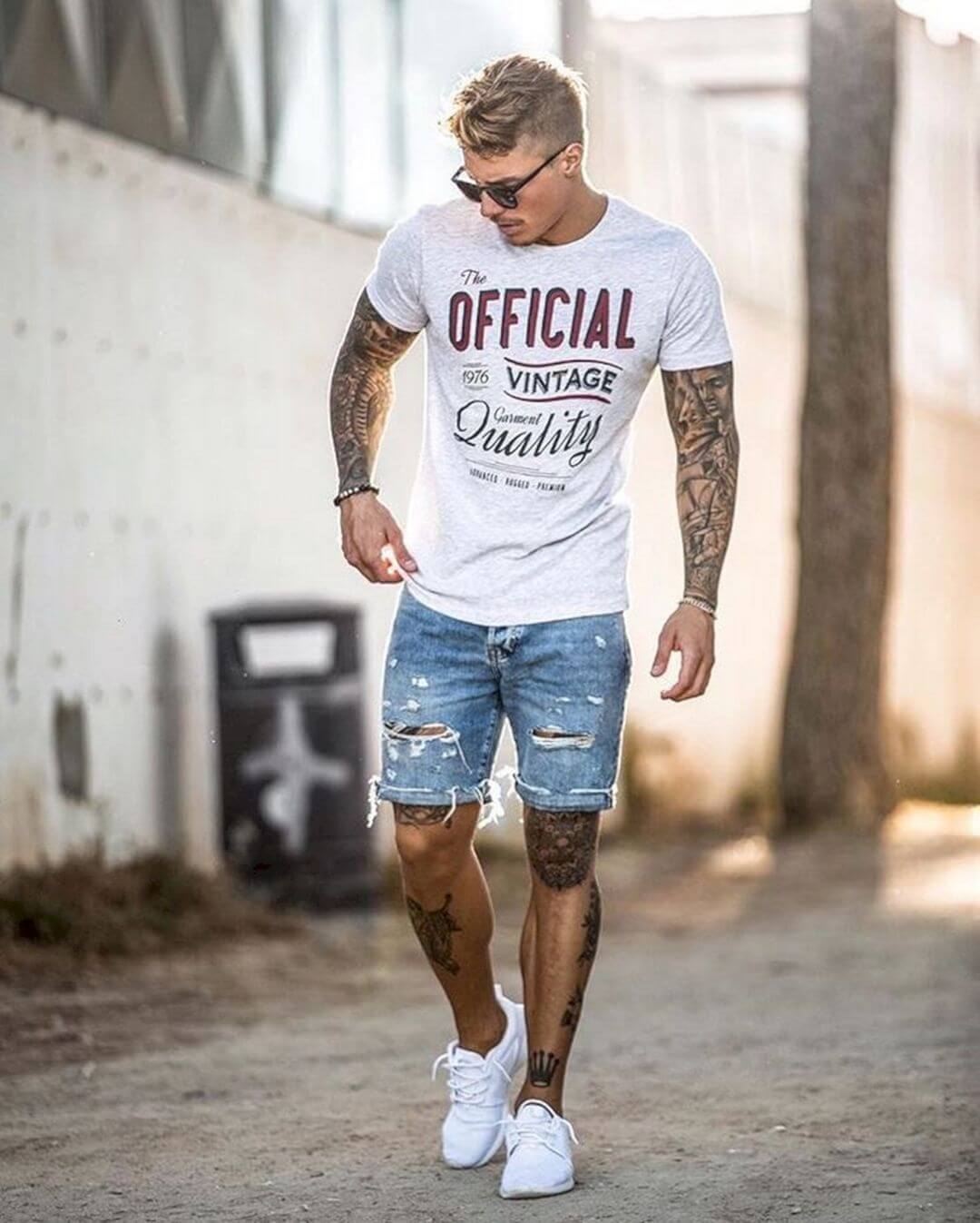 A man walking down a street wearing ripped shorts
