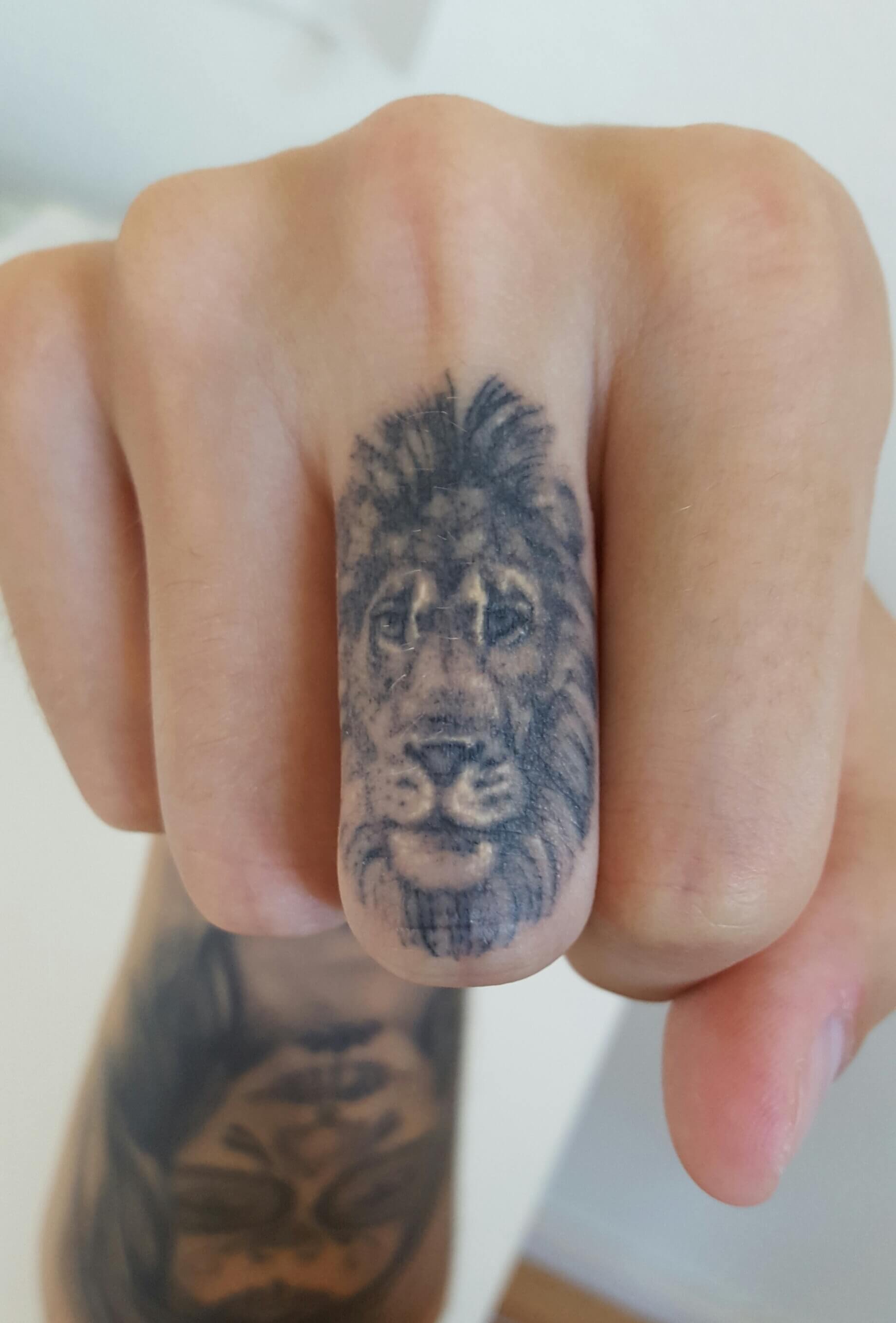 Lion Skull On The Middle Finger Tattoo