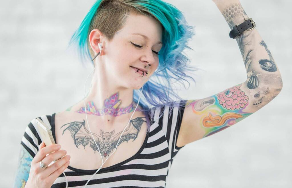 A woman with blue hair and tattoos on her body
