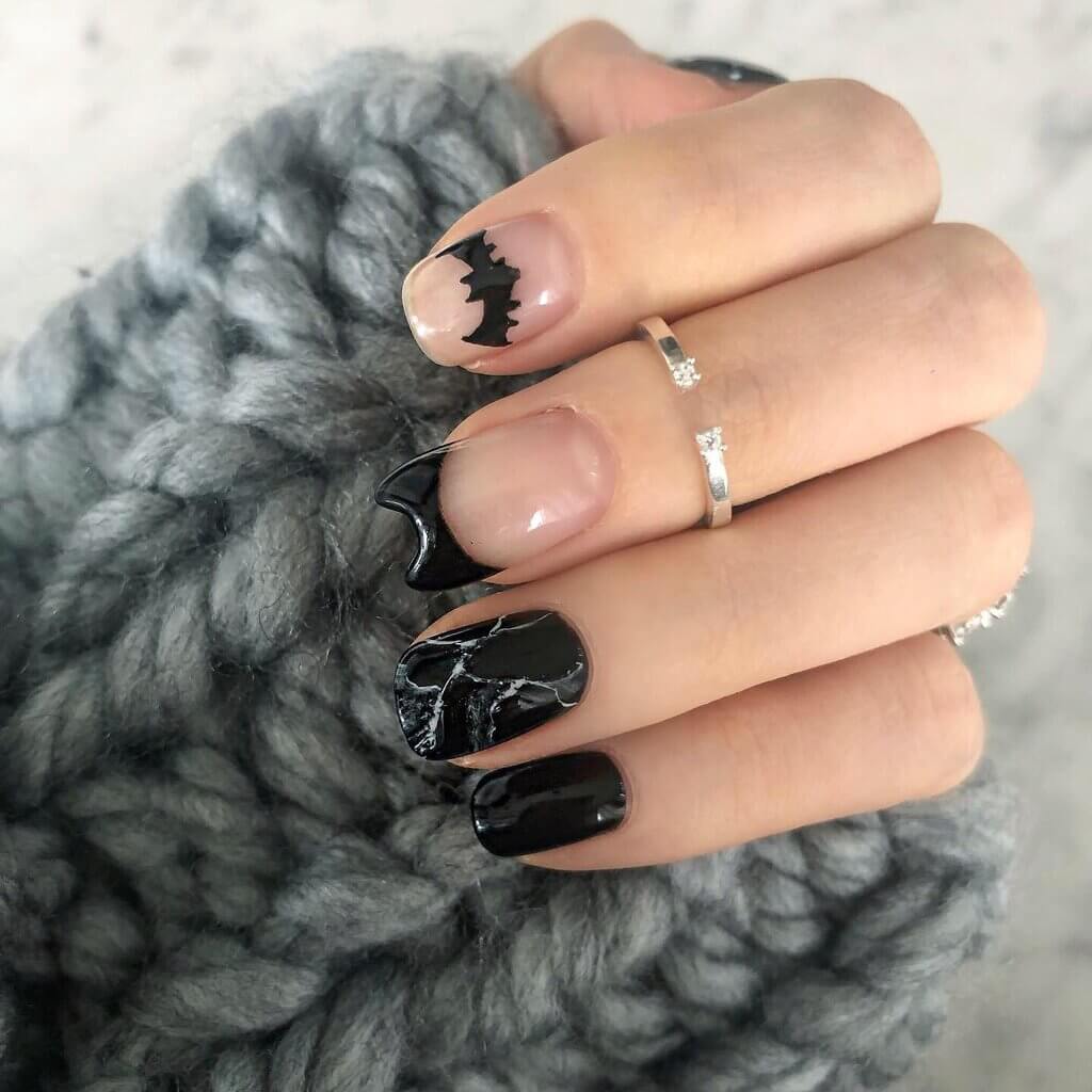 A woman's hand with a black and white manicure with batman design 
