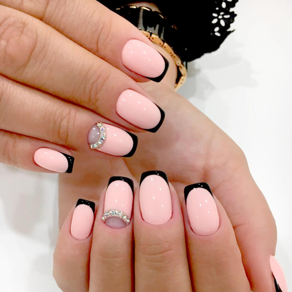 A woman's hands with pink and black nail polish

