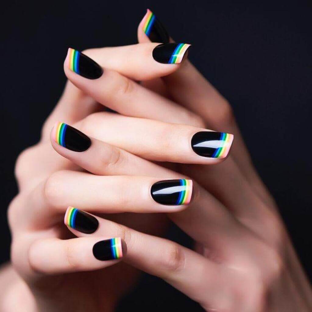 A woman's hands with black and white nail polish with Colorful tip
