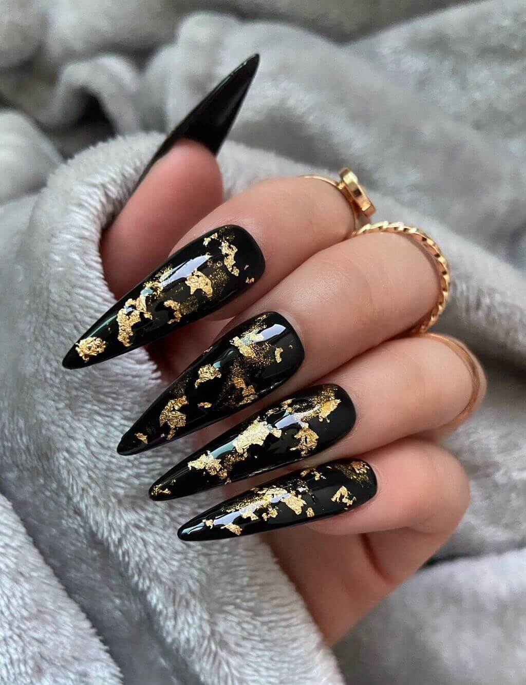 A woman's hand with black and gold nail polish
