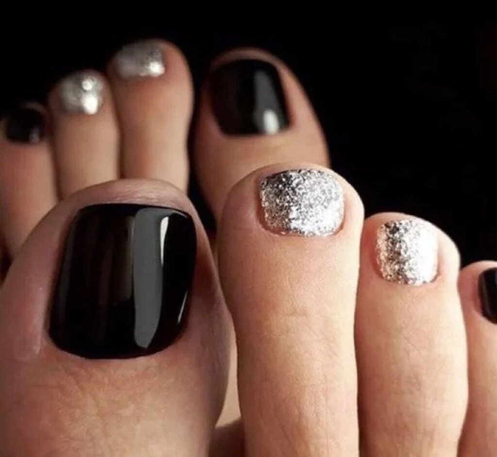 A woman's feet with black and silver toenails
