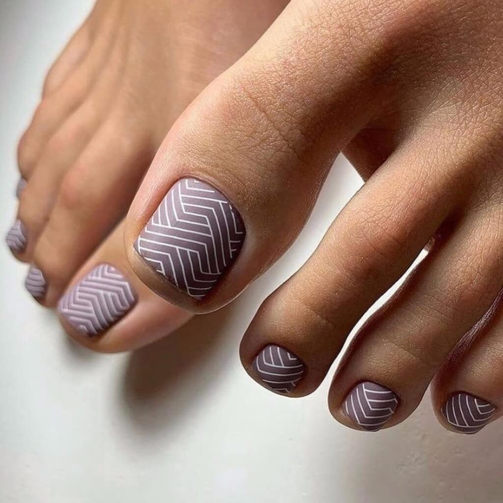 A woman's feet with a purple and white manicure
