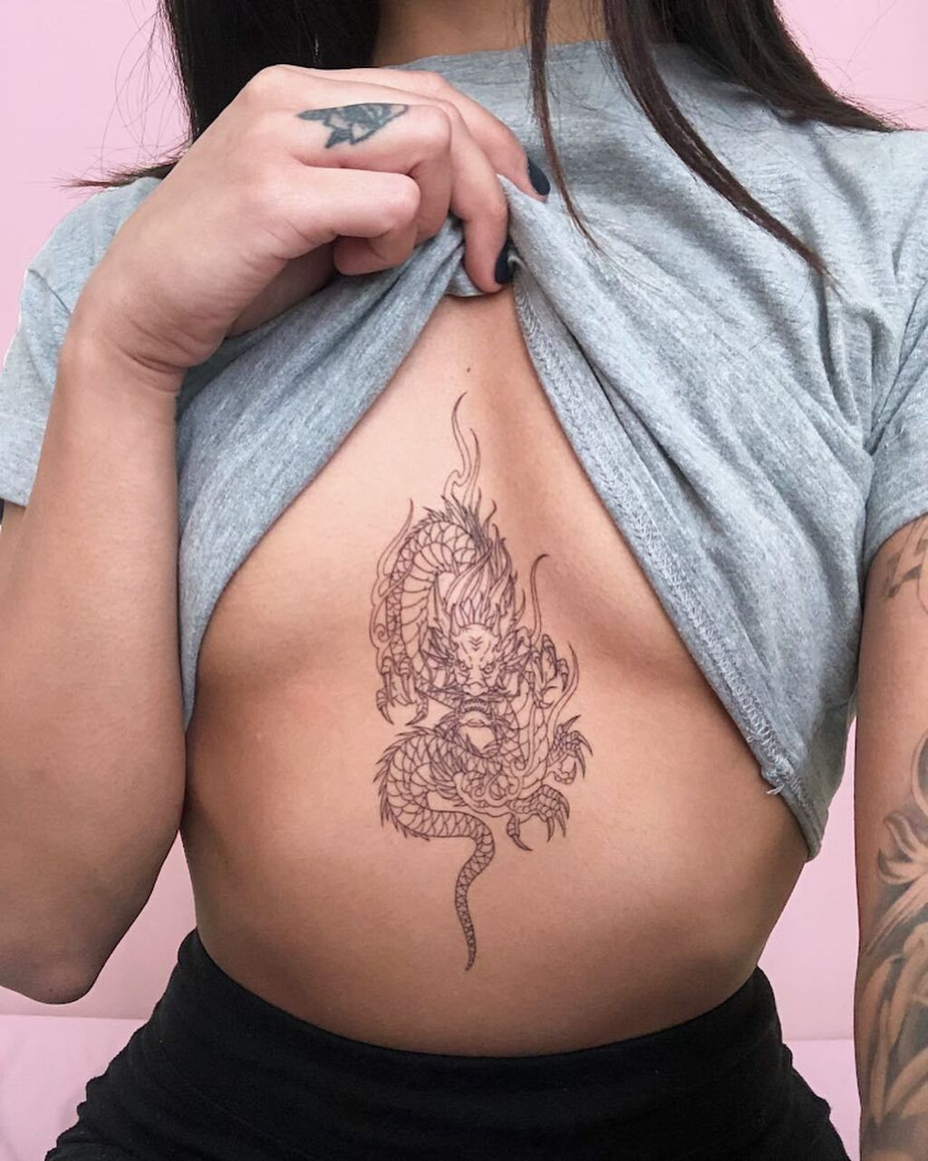 A woman with a dragon tattoo under her breast
