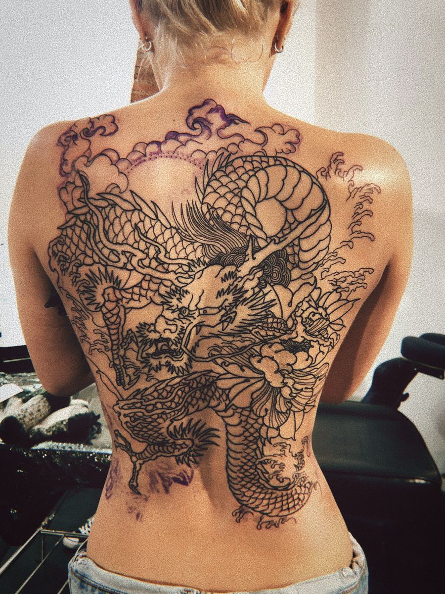 A woman with Japanese dragon tattoos her back
