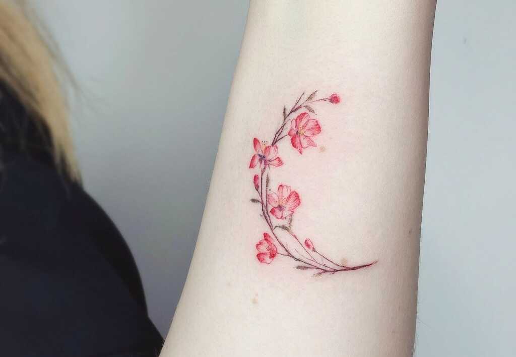 A woman's arm with  cherry blossom tattoos on her hand