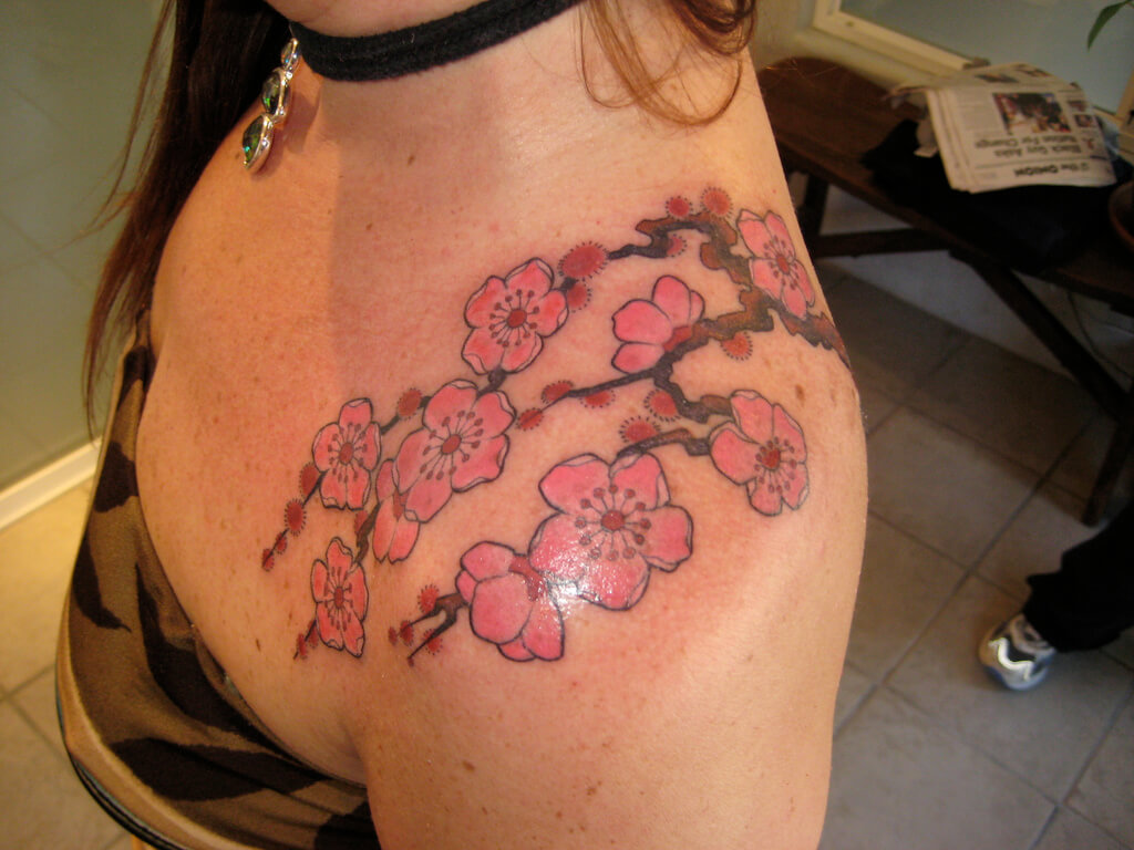 A woman with a cherry blossom tattoo on her shoulder
