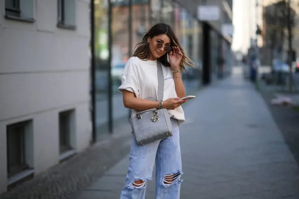 A woman standing on a sidewalk and hold cell phone
