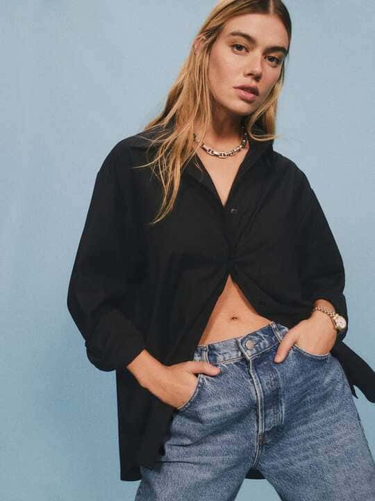A woman wearing a black oversized shirt and jeans
