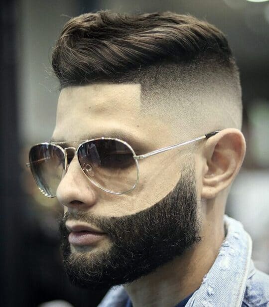 A close up of a man with a beard and mid fade haircut

