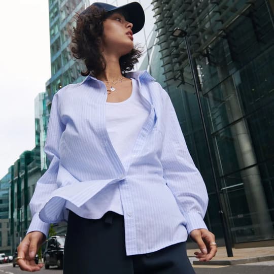 A woman in a blue oversized shirt and black pants
