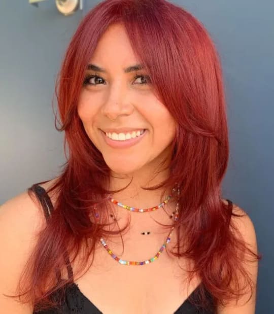 A woman with red layered hair with curtain bangs