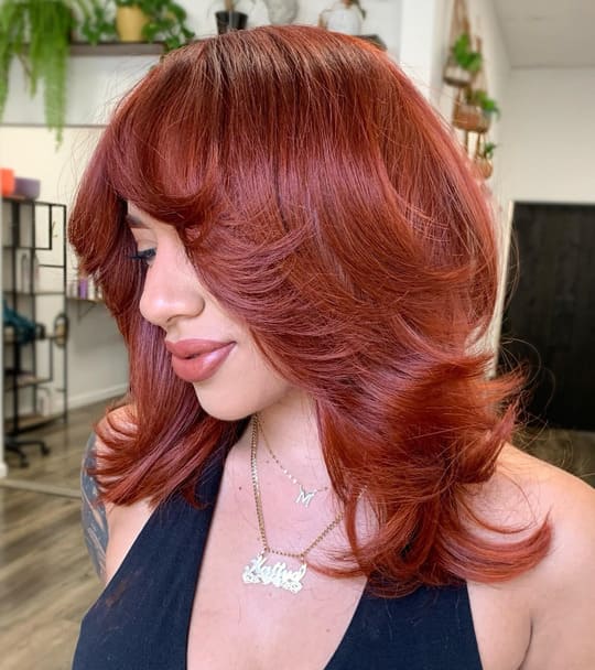 red layered hair with curtain bangs