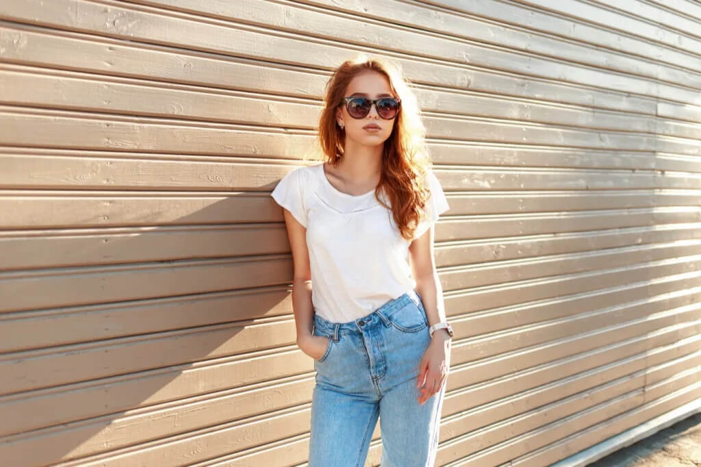 women waring a white top and blue jeans with sunglass